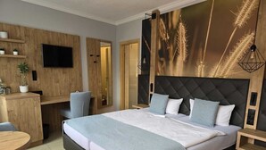 A modern hotel room with a large bed, a desk, and a TV. - Pension Marlis (Moritzburg)