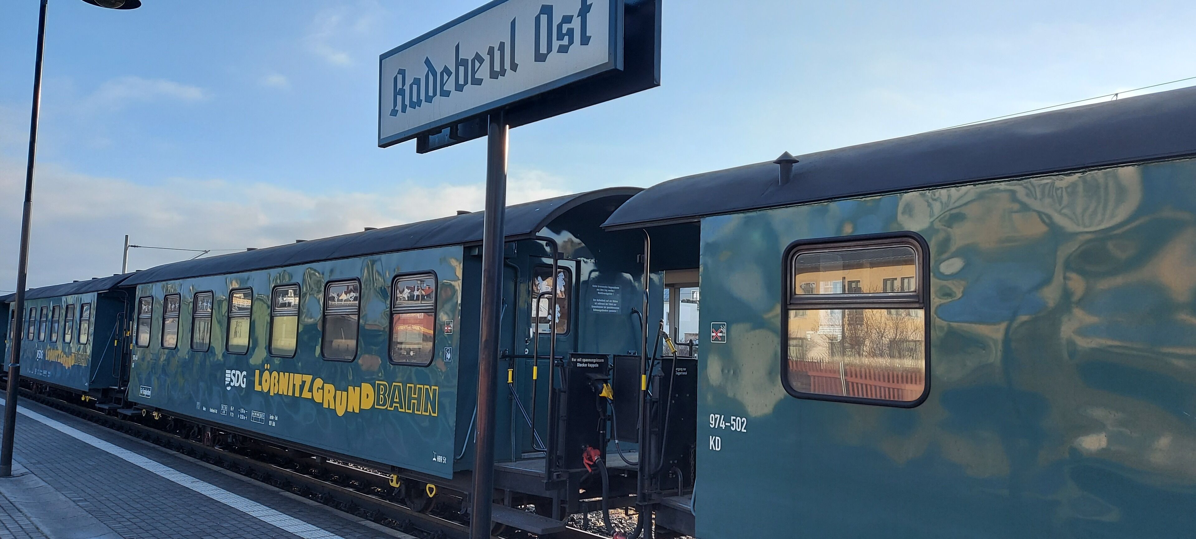 A train with a sign reading "Radebeul Ost" at a station platform.