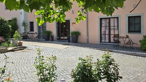A courtyard with cobblestone pavement, potted plants, and outdoor seating. - Pension Marlis (Moritzburg)