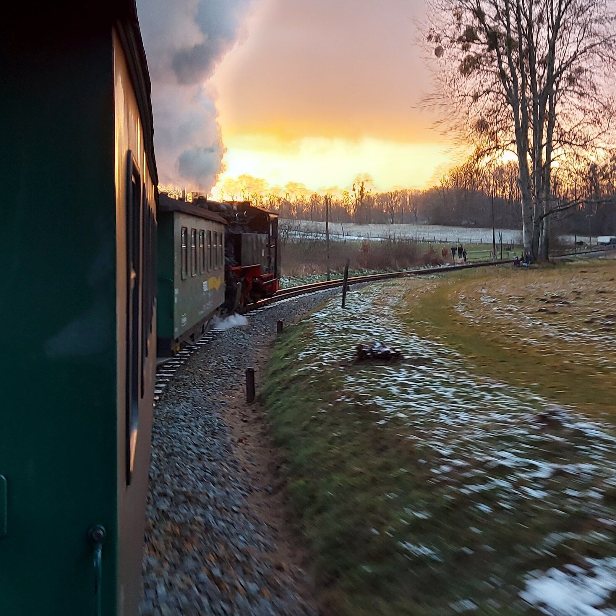 A train moving along tracks with a sunset in the background.