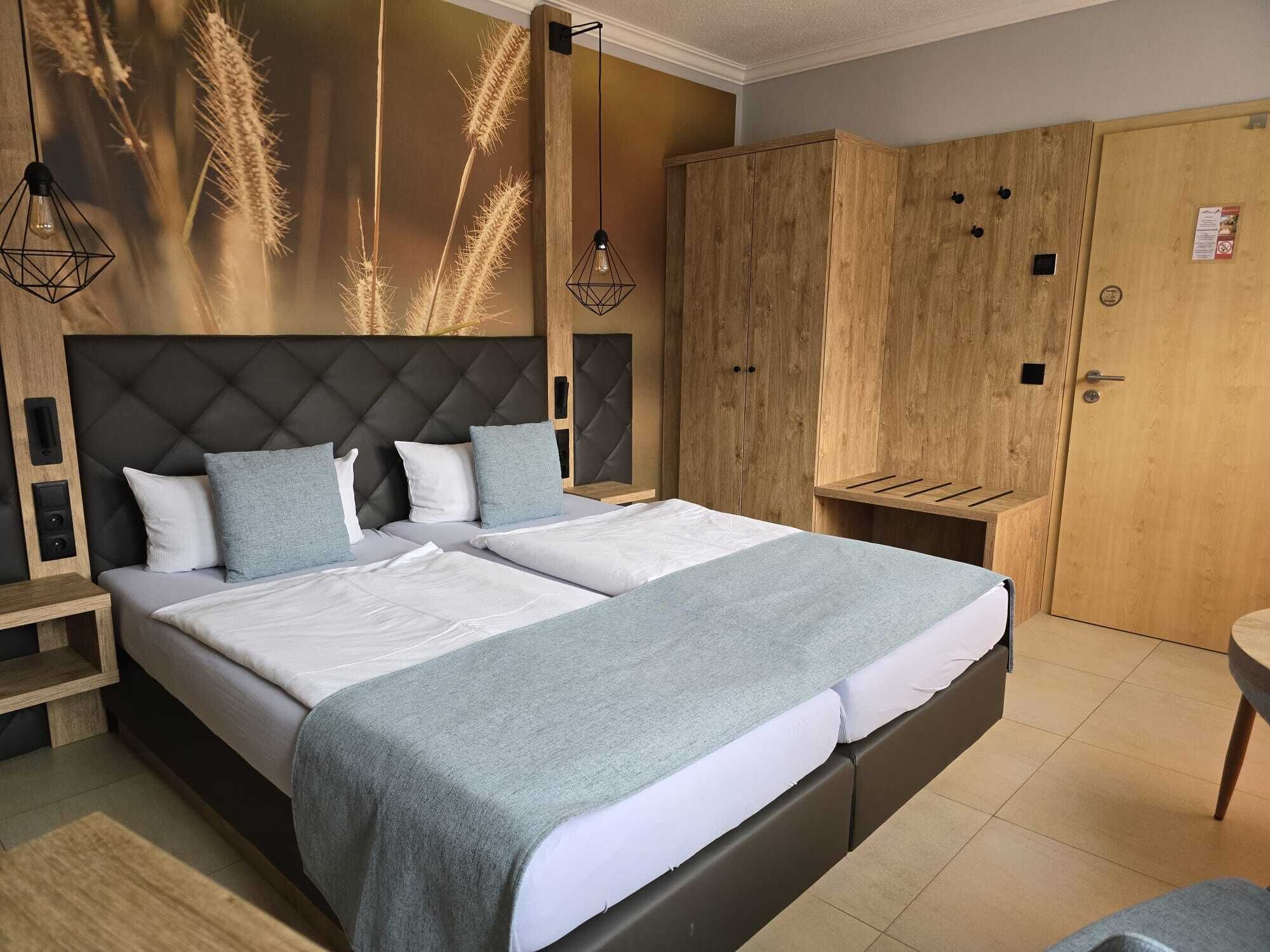 A modern bedroom with a large bed, wooden wardrobe, and a bedside table.