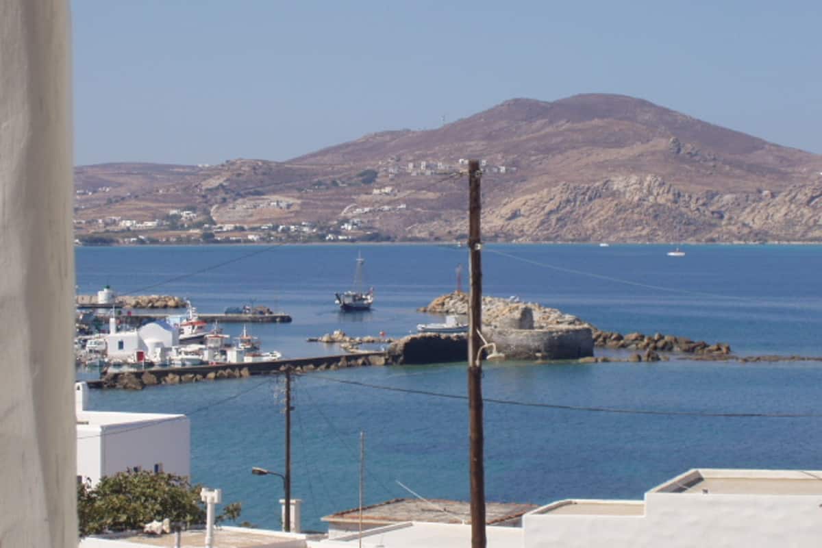 A coastal town with a harbor, boats, and a mountainous backdrop.