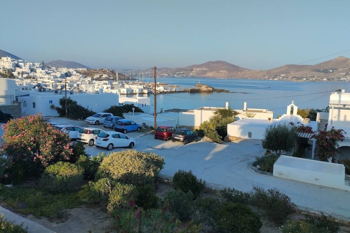 A coastal town with white buildings, a marina, and parked cars.