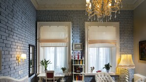 A room with a brick wall, a chandelier, a bookshelf, and a seating area with a table and chairs. - Hotel 19 (Kharkiv)