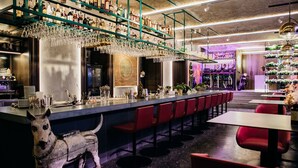 A bar area with a long counter, red bar stools, and a decorative dog statue. - Hotel 19 (Kharkiv)