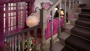A multi-level interior with a staircase, decorative lighting, and a wall adorned with framed pictures. - Hotel 19 (Kharkiv)