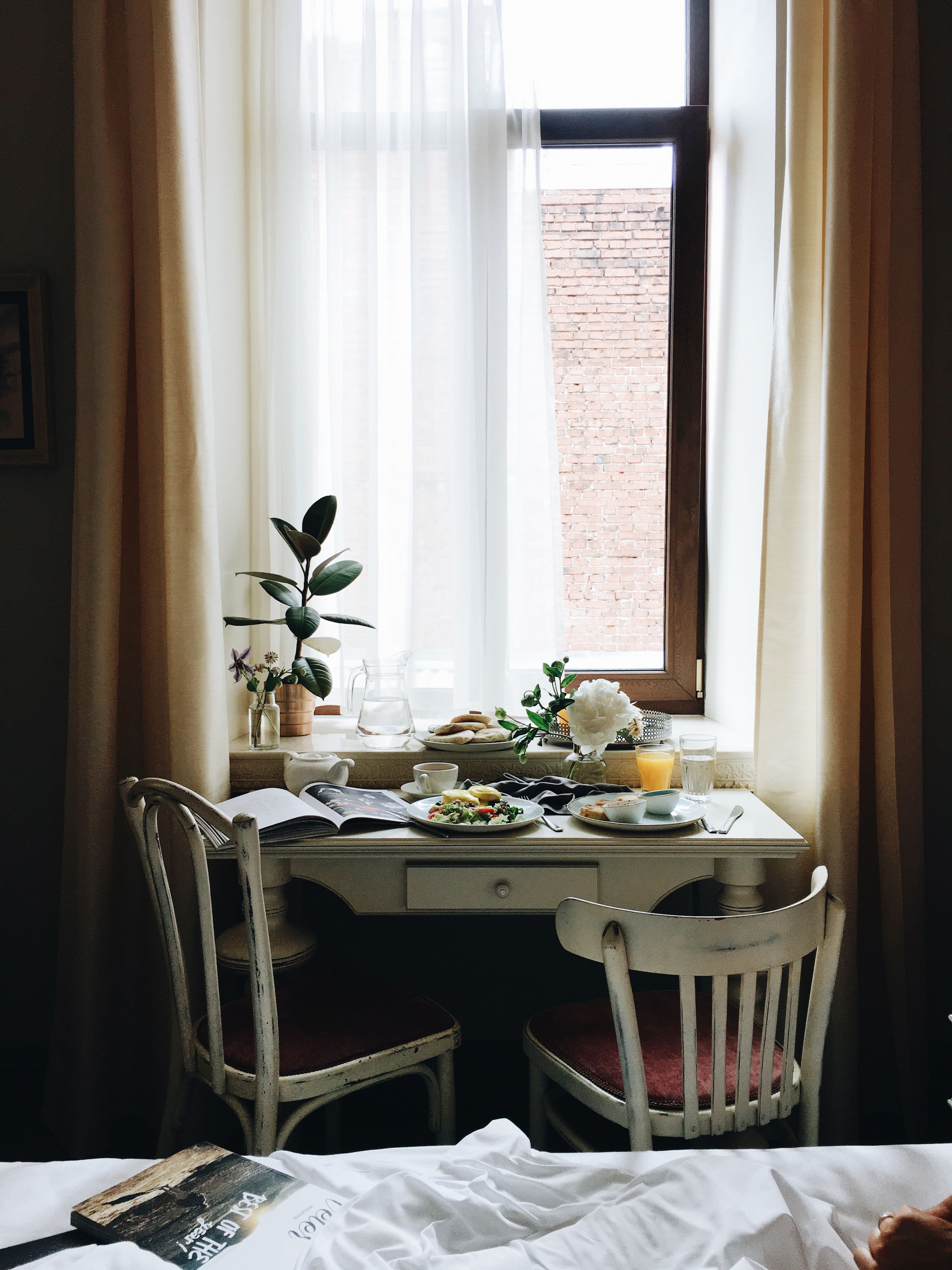 A dining area with a table set for breakfast, including plates of food, a pitcher, and a cup.