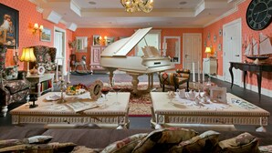 Una sala imponente con un piano de cola, muebles ornamentados y un candelabro.