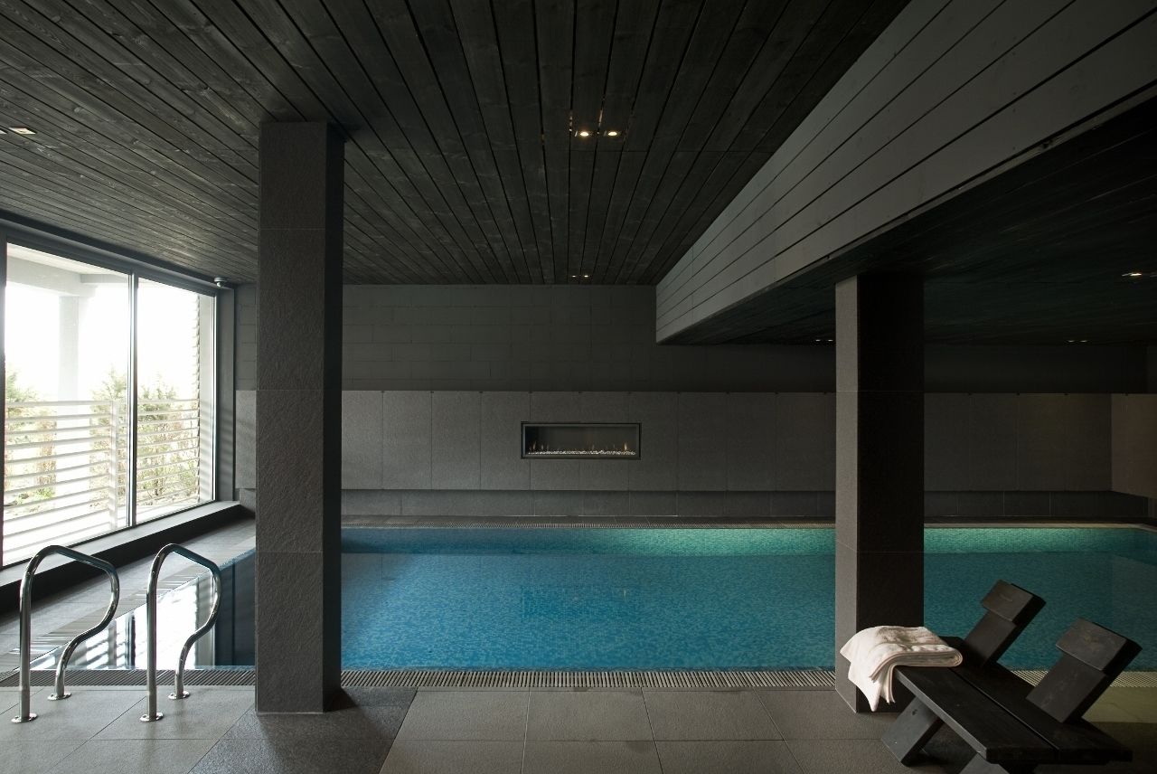 Una piscina interior con vistas al exterior, un banco y una pantalla montada en la pared.