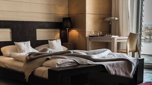 A neatly made bed with a blanket, a bedside table with a lamp, and a chair. - Hotel Galery69 (Stawiguda)
