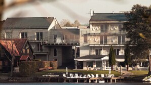A waterfront property with a dock, lounge chairs, and a building with multiple stories and balconies. - Hotel Galery69 (Stawiguda)