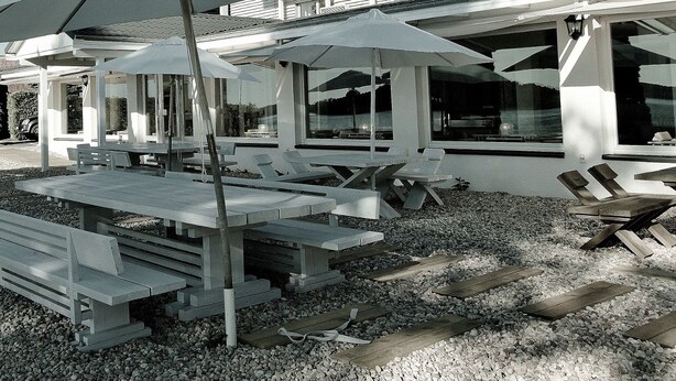 A beachfront property with outdoor seating and umbrellas, a building with multiple balconies, and a view of the sea. - Hotel Galery69 (Stawiguda)
