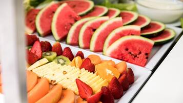 Una bandeja de frutas con sandía, fresas, kiwi, naranja y rodajas de plátano.