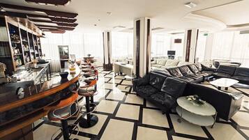 A modern hotel lobby with a bar area, leather seating, and a check-in counter.