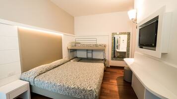 Una habitación pequeña con una cama litera, una mesita de noche, un televisor montado en la pared y un taburete.