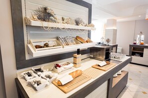 A hotel reception area with a counter displaying various amenities like cutlery, bread, and decorative items. - Hotel Alexander (Cattolica)