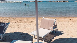 Una spiaggia con due lettini e un ombrellone.