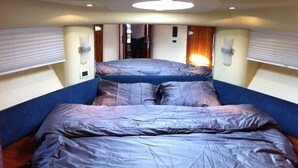 A compact room with two beds, a ceiling light, and a door leading to another area. - Une Nuit à Bord Bandol (Bandol)