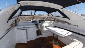 A boat's interior with a dining area, a small kitchen, and a view of the marina. - Une Nuit à Bord Bandol (Bandol)
