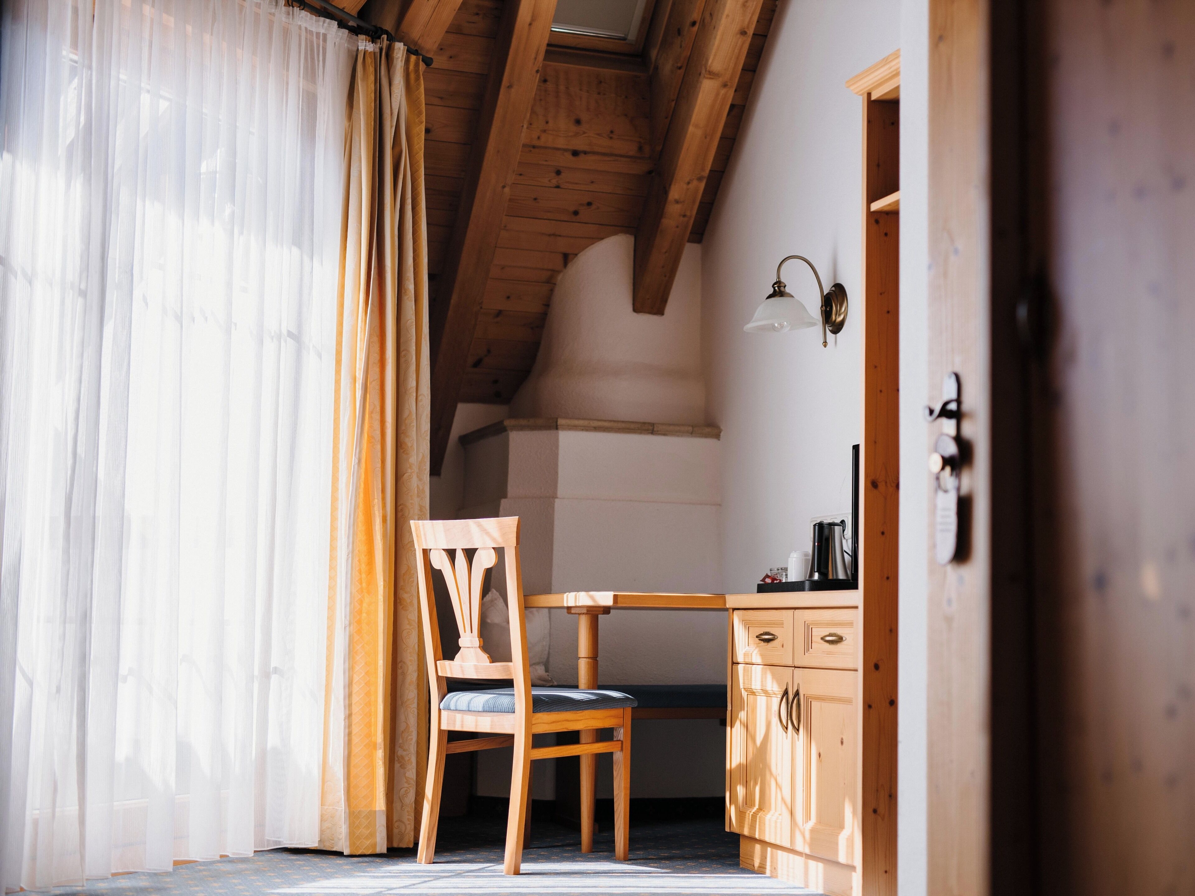 A room with a wooden ceiling, a chair, a table, and a cabinet.