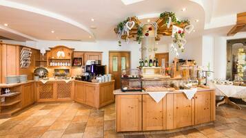 A spacious kitchen with wooden cabinets, a central island with food displays, and a decorative ceiling.