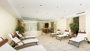 Un salon intérieur moderne avec des murs en verre, de nombreux fauteuils confortables et un espace de détente central.