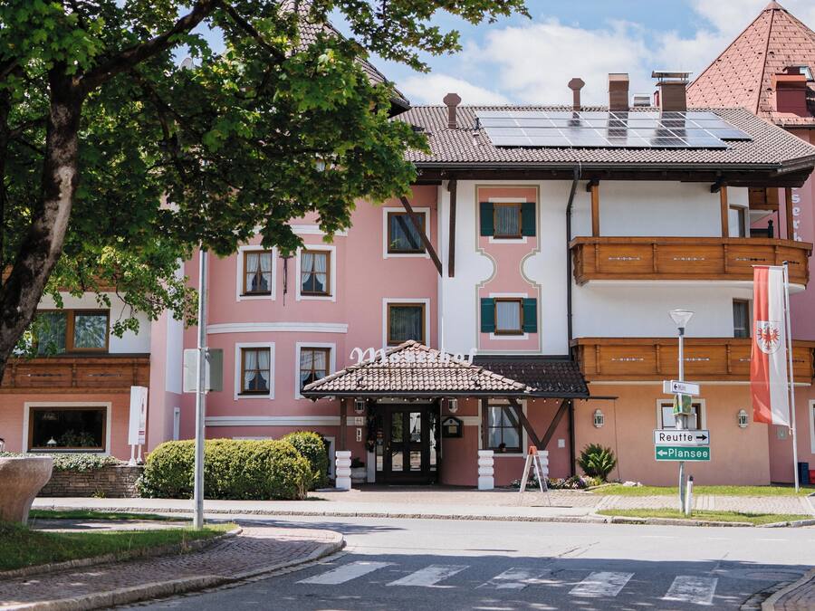 A hotel with a traditional architectural style, featuring a tiled roof and a balcony.