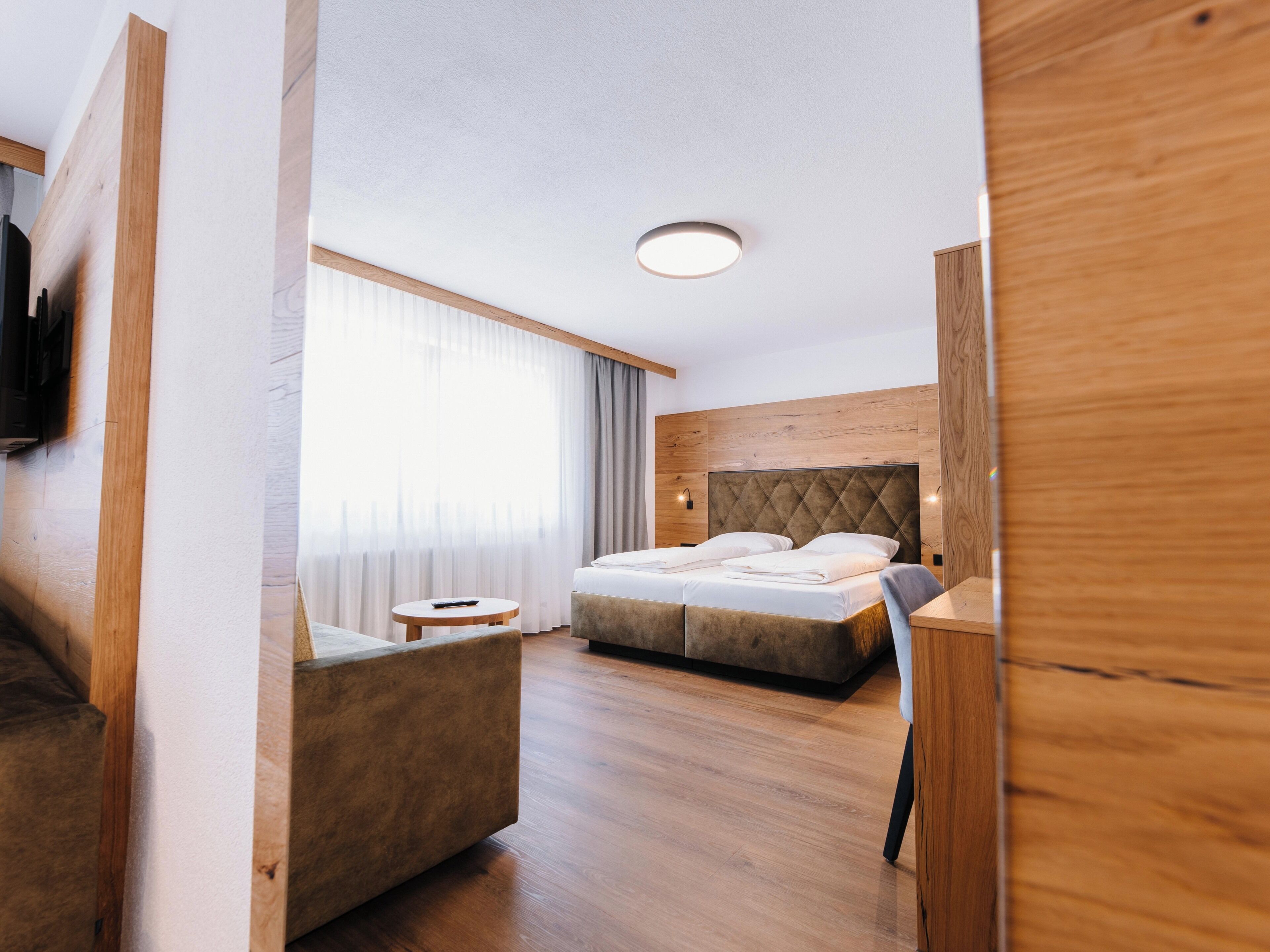 Una habitación de hotel moderna con una cama grande, una pequeña mesa redonda y un espacio para sentarse.