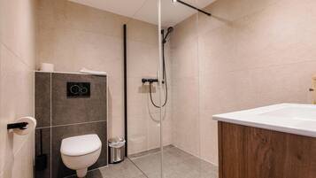 A modern bathroom with a toilet, bidet, and shower.