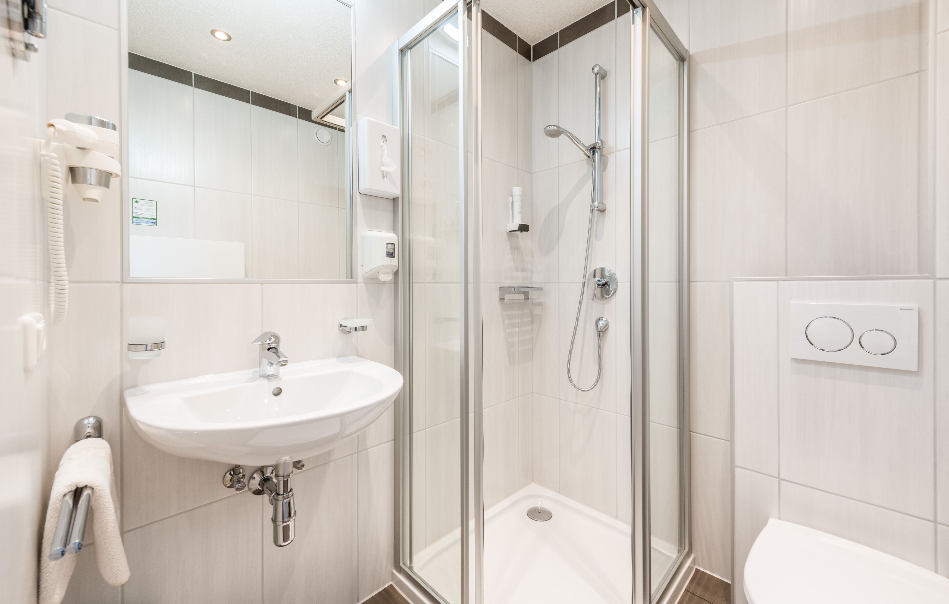 A modern bathroom with a glass-enclosed shower, a white sink, and a toilet.