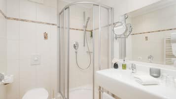 A modern bathroom with a glass-enclosed shower, a white sink with a mirror, and a toilet.