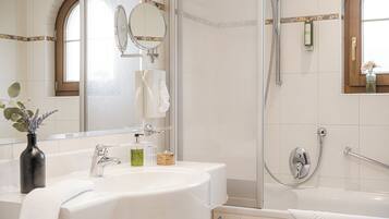 A modern bathroom with a large mirror, a sink, and a shower area.