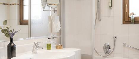 Une salle de bain moderne avec un grand miroir, un lavabo et un espace douche.