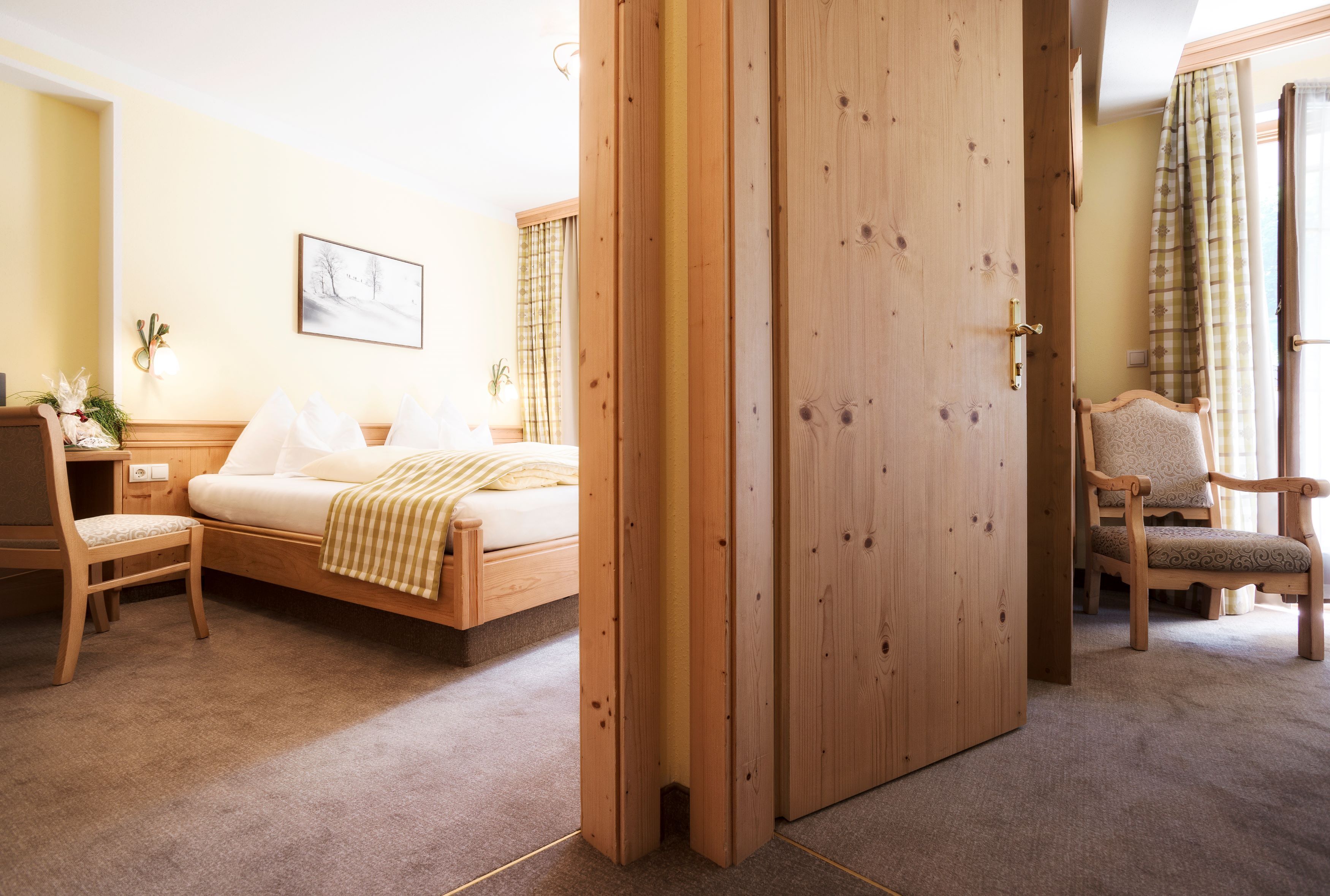 Une chambre d’hôtel avec un lit en bois, une chaise, un bureau et une armoire.