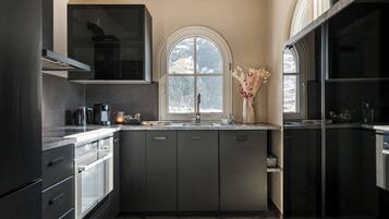 Una cocina moderna con armarios oscuros, un ventanal y vistas a un paisaje nevado.