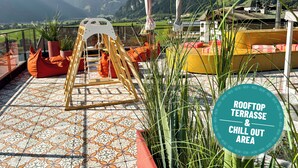 A rooftop terrace with a swing set, seating, and potted plants. - Hotel Sieghard (Schwendau)
