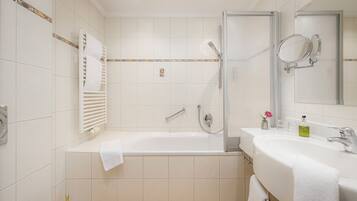 A modern bathroom with a bathtub, a shower, a sink with a mirror, and a towel rack.