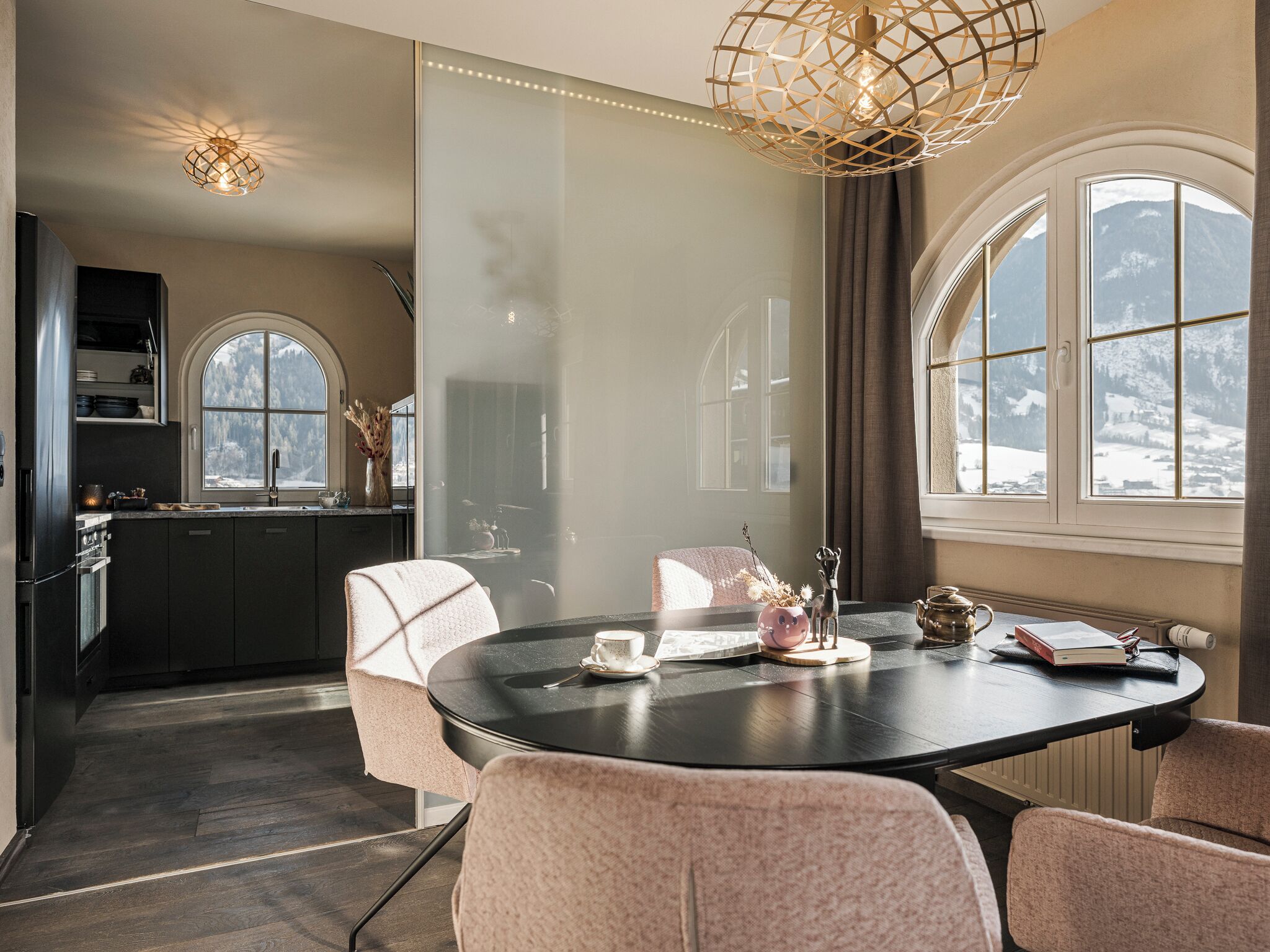 Uma sala de jantar moderna com uma mesa redonda, cadeiras e um lustre decorativo.