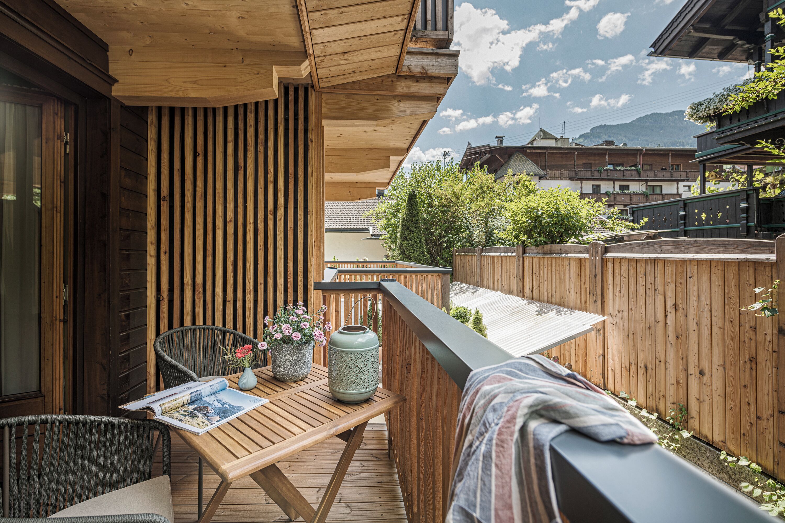 Una terraza de madera con una mesa, sillas y una revista.