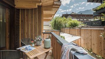 A wooden deck with a table, chairs, and a magazine.