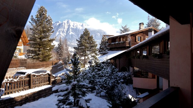 Un paisaje montañoso cubierto de nieve con un chalet de madera y un edificio de piedra en primer plano.