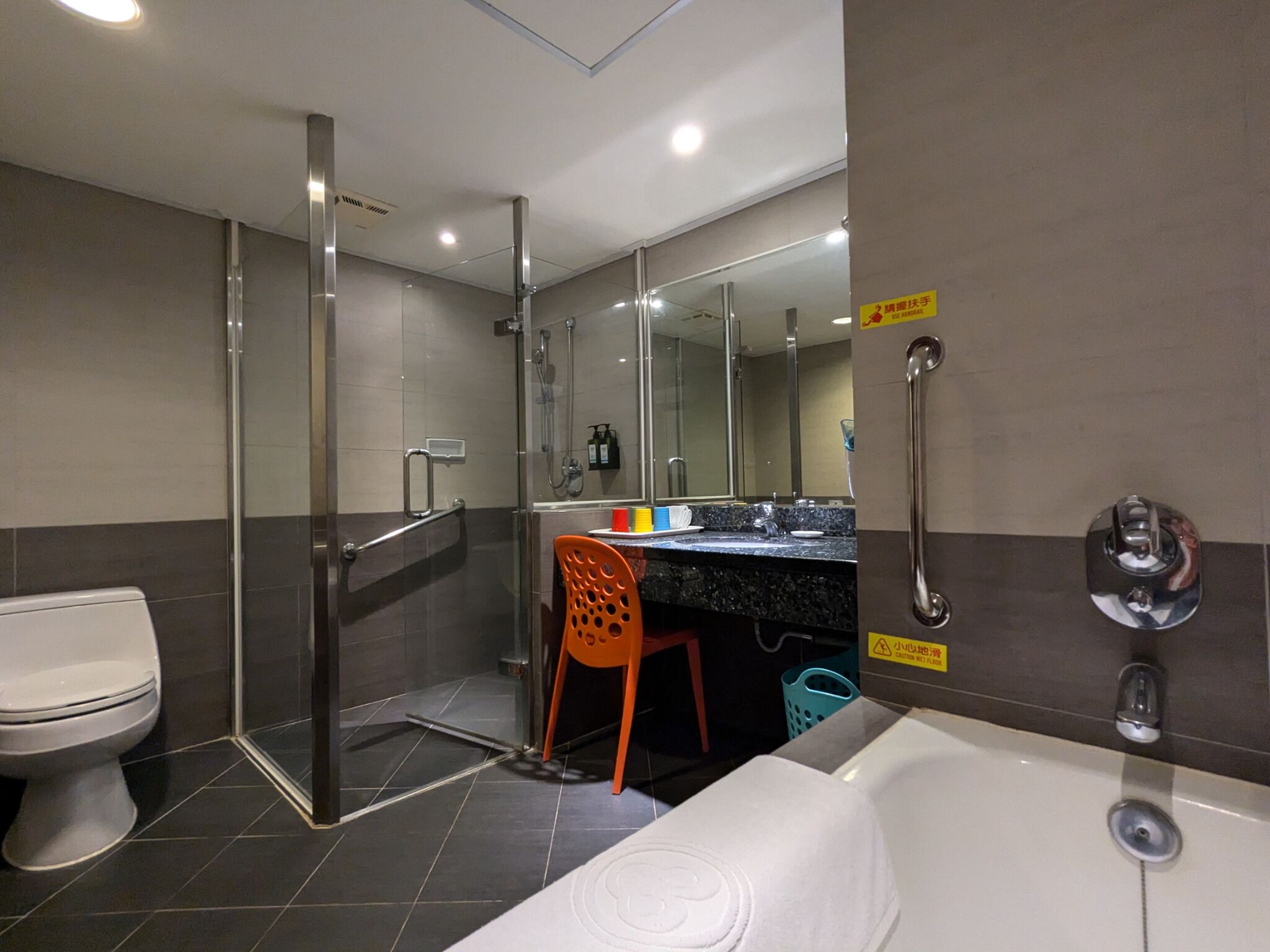 Un baño moderno con ducha de vidrio, inodoro, lavamanos con espejo y bañera.