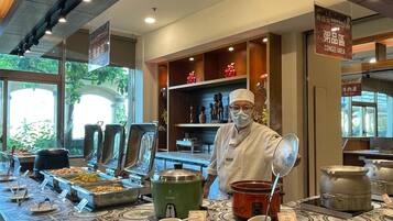 A buffet area with various food stations, a chef, and a congee area.