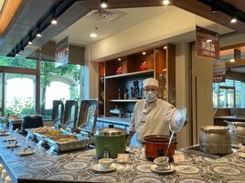 A buffet area with various food stations, a chef, and a congee area.