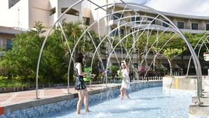 A swimming pool with a water fountain feature, surrounded by a tiled deck and greenery. - Howard Beach Resort Kenting (Hengchun)