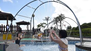 A water feature with a metal arch structure, a tiled pool, and a wooden fence with decorative elements.