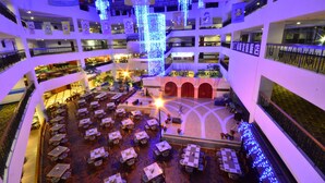 A multi-level atrium with tables and chairs arranged for dining, surrounded by balconies and illuminated by blue lights. - Howard Beach Resort Kenting (Hengchun)