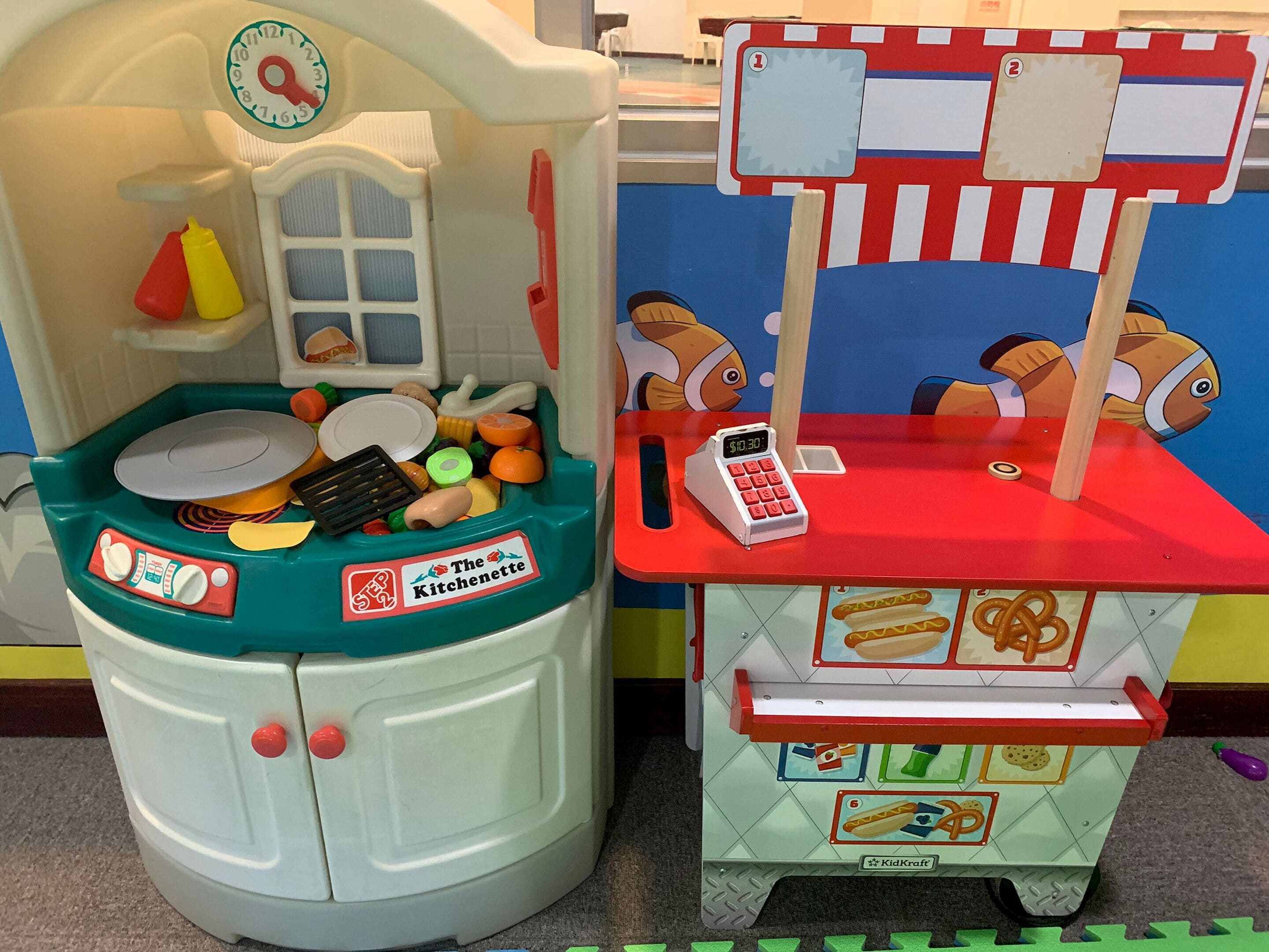 A toy kitchen setup with a sink, stove, and a cash register.