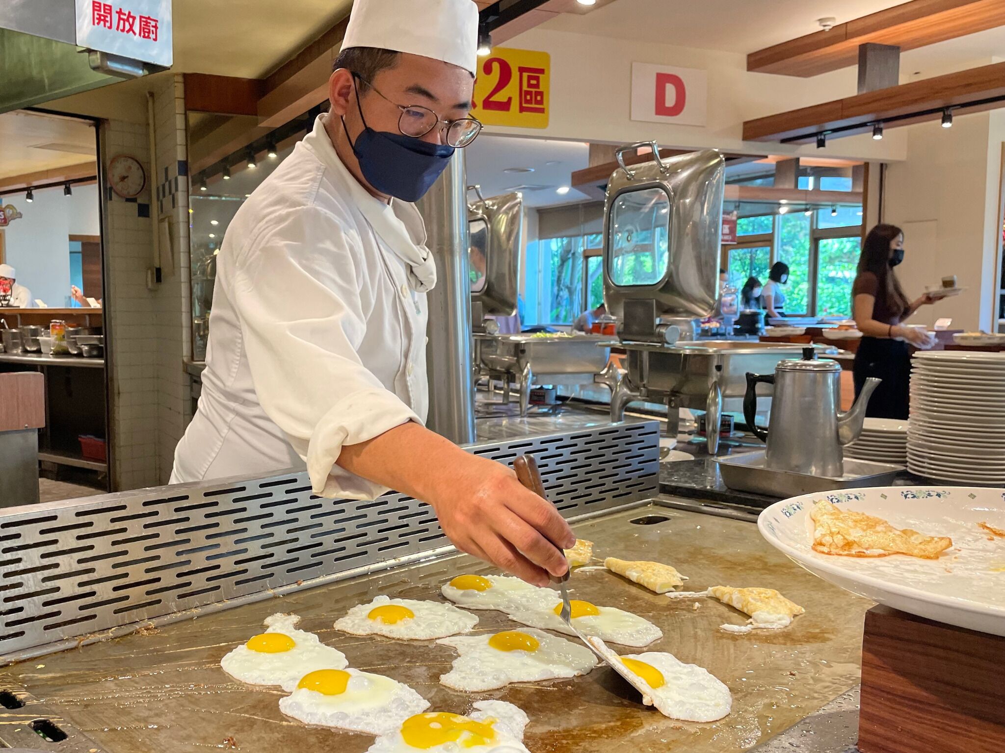 A chef preparing eggs on a griddle in a restaurant.