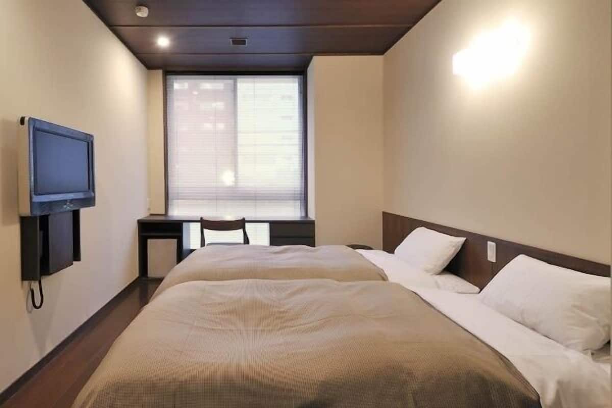 Una camera d'albergo con un letto, una televisione, una scrivania e una finestra.
